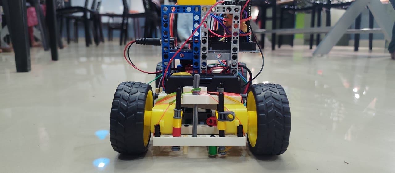 The LEGO prototype we took to Regionals: a LEGO frame on a small four-wheeled base with yellow motors and exposed red, black and green wires.